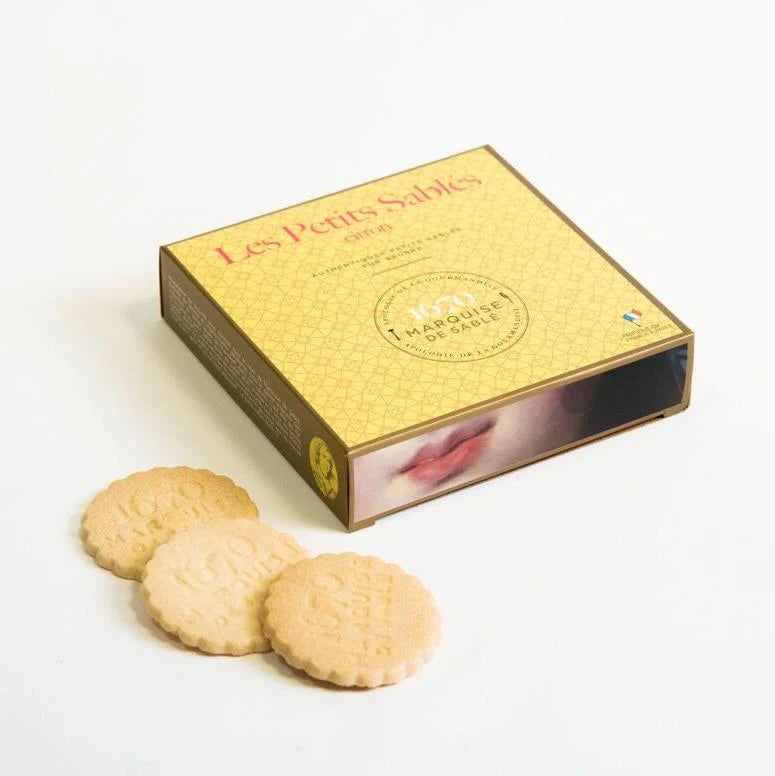 Gold box of 'Les Petits Sablés' cookies with three cookies in front on a white background