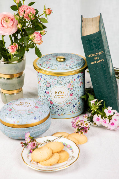 Decorative cookie jars with floral designs on a table with cookies and flowers.
